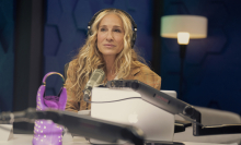 Sarah Jessica Parker as Carrie Bradshaw, Carrie sits in her podcast studio wearing headphones with a pensive expression.