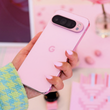 A phone with rose pink painted nails holds a rose pink Pixel 9 Pro.