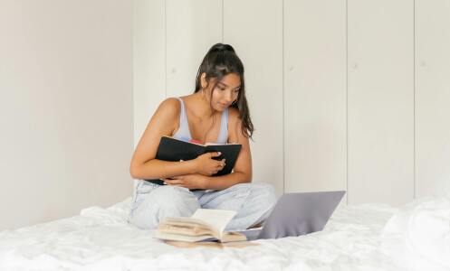 Girl holding laptop on bed