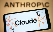 The Claude app logo on a smartphone in front of a projection of the Anthropic logo