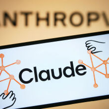 The Claude app logo on a smartphone in front of a projection of the Anthropic logo