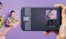 Kodak instant camera taking photo of woman holding flowers