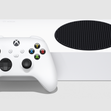 an xbox series s lying on its side next to an xbox wireless controller