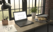 Lenovo Chromebook sitting atop desk next to pad of paper and stack of magazines