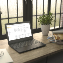 Lenovo Chromebook sitting atop desk next to pad of paper and stack of magazines