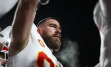 Travis Kelce of the Kansas City Chiefs stands on a football field with his helmet off.