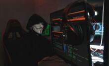 Hacker in guy fawkes mask by computer displays