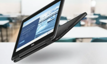 Dell 2-in-1 Chromebook shown hovering in the air above desks in a school setting