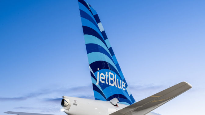 Plane with JetBlue logo on tail flying through sky