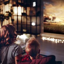 A family is watching a movie on a wall thanks to a projector