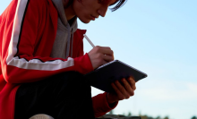 A person holding an iPad Air while sitting outside