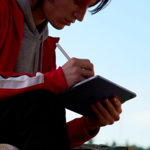 A person holding an iPad Air while sitting outside