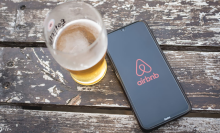 airbnb logo on phone next to beer on table