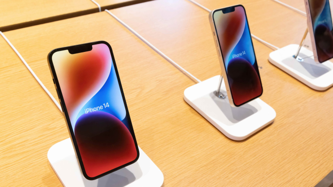 Apple iPhone 14 models standing on a table.