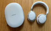 A pair of Bose QuietComfort Ultra headphones and case on a wooden table