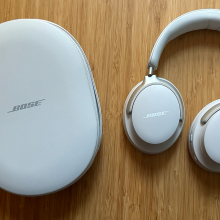 A pair of Bose QuietComfort Ultra headphones and case on a wooden table