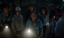 The "Stranger Things" cast hold flashlights and look up at something mysterious in their search for the villain Vecna.