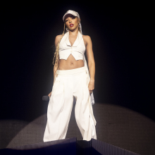 Tinashe performing at Coachella in a white vest, pants, and baseball cap. 