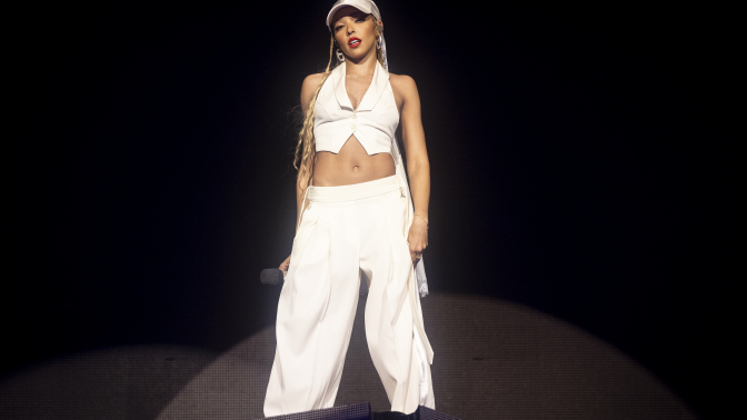 Tinashe performing at Coachella in a white vest, pants, and baseball cap. 