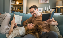 Adult couple man and woman Caucasian husband and wife in a relationship real book hold books on the sofa bed at home in the apartment reading leisure bonding family concept real people copy space