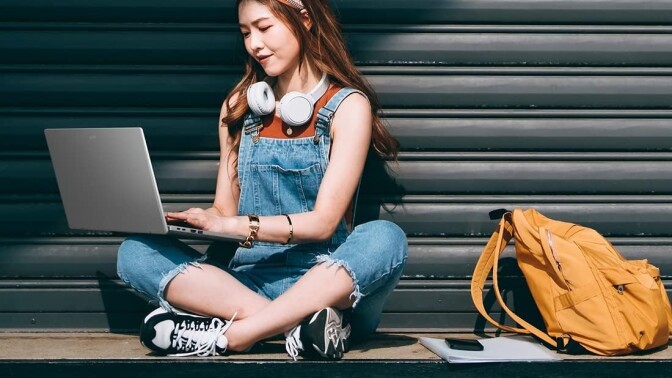 a woman sits on the ground with an acer laptop in her lap while she's typing