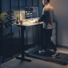 man using iQ Slim Walking Pad at night while working