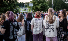 Taylor Swift fans decked out in merch standing in a crowd. 