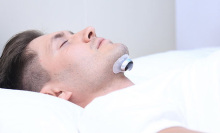 Person using the Snore Circle Anti-Snoring Sleep Aid Muscle Stimulator.