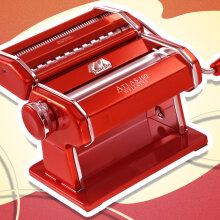 An illustration featuring a red Marcato Atlas manual pasta machine on a yellow and red graphic background.