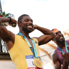  Gold medalist Noah Lyles poses with a miniature Eiffel Tower