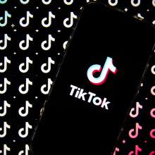 TikTok logo is displayed on a smartphone screen then replicated in pattern behind it.