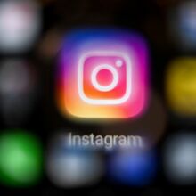 The Instagram app logo on a black blurred background