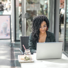 a woman sits outside a cafe working on her laptop