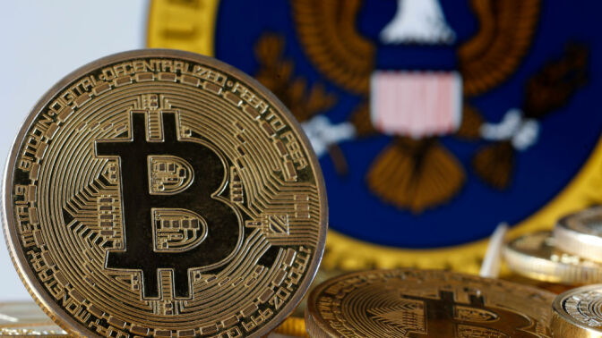 , A visual representation of the digital cryptocurrency Bitcoin is displayed in front of Securities and Exchange Commission (SEC) logo.