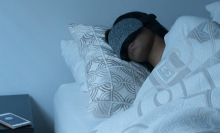 Person sleeping in bed wearing grey sleeping mask