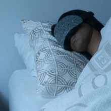 Person sleeping in bed wearing grey sleeping mask
