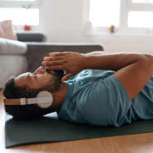 A man laying on the floor in a relaxed pose listening to headphones. 