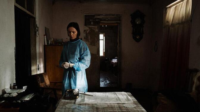 A woman in surgical dress stands alone in a room.