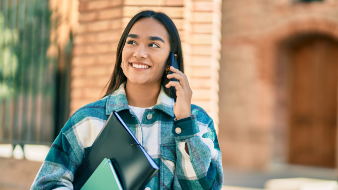 Young latin student girl smiling happy using smartphone at the city. - stock photo