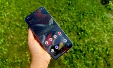 Google Pixel 9 Pro XL with water droplets on its screen with grass in the background