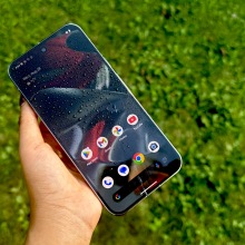 Google Pixel 9 Pro XL with water droplets on its screen with grass in the background