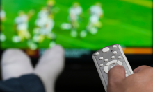 person lounging on couch watching football