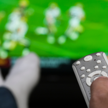 person lounging on couch watching football