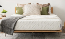 bare mattress with pillows and blanket draped over it