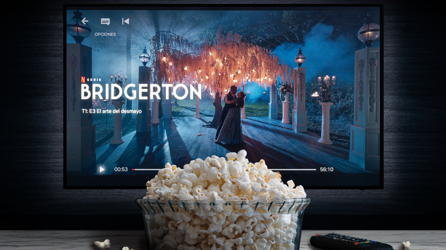 A TV screen is paused on the Netflix show "Bridgerton" with a bowl of popcorn sitting in front of it.