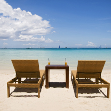 Two lounge chairs and table with drinks sitting on beach