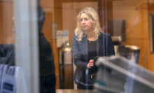 A blonde woman is seen through a see-through glass panel in a court building.