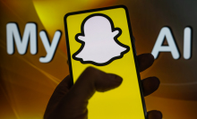 A phone displays the Snapchat logo in front of a screen that reads "My AI". 