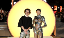 Timothee Chalamet and Zendaya on the 'Dune: Part 2' red carpet illuminated by a glowing yellow circle behind them.