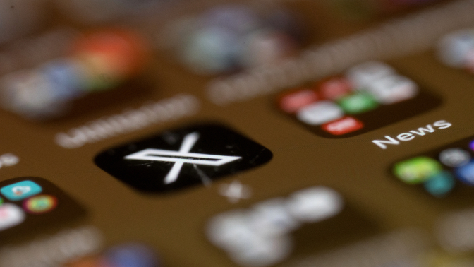 A blurry phone screen, with only the X app logo in focus. 